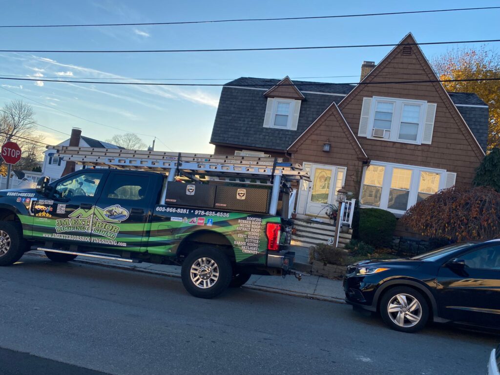 A JM Exteriors Roofing Siding service truck parked in front of a residential home, showcasing the company's commitment to honesty and transparency with every roofing project in Tewksbury, MA.