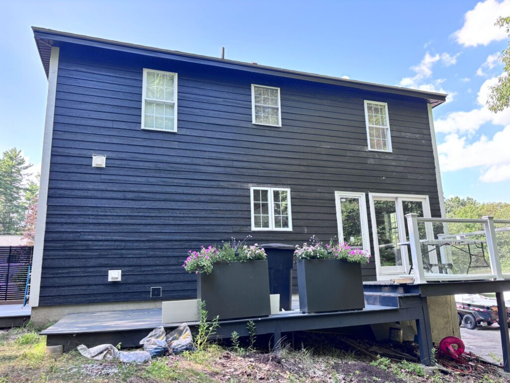 A completed premium siding installation in Chelmsford, MA, showcasing modern dark horizontal panels installed by JM Exteriors Roofing Siding, a professional siding contractor.